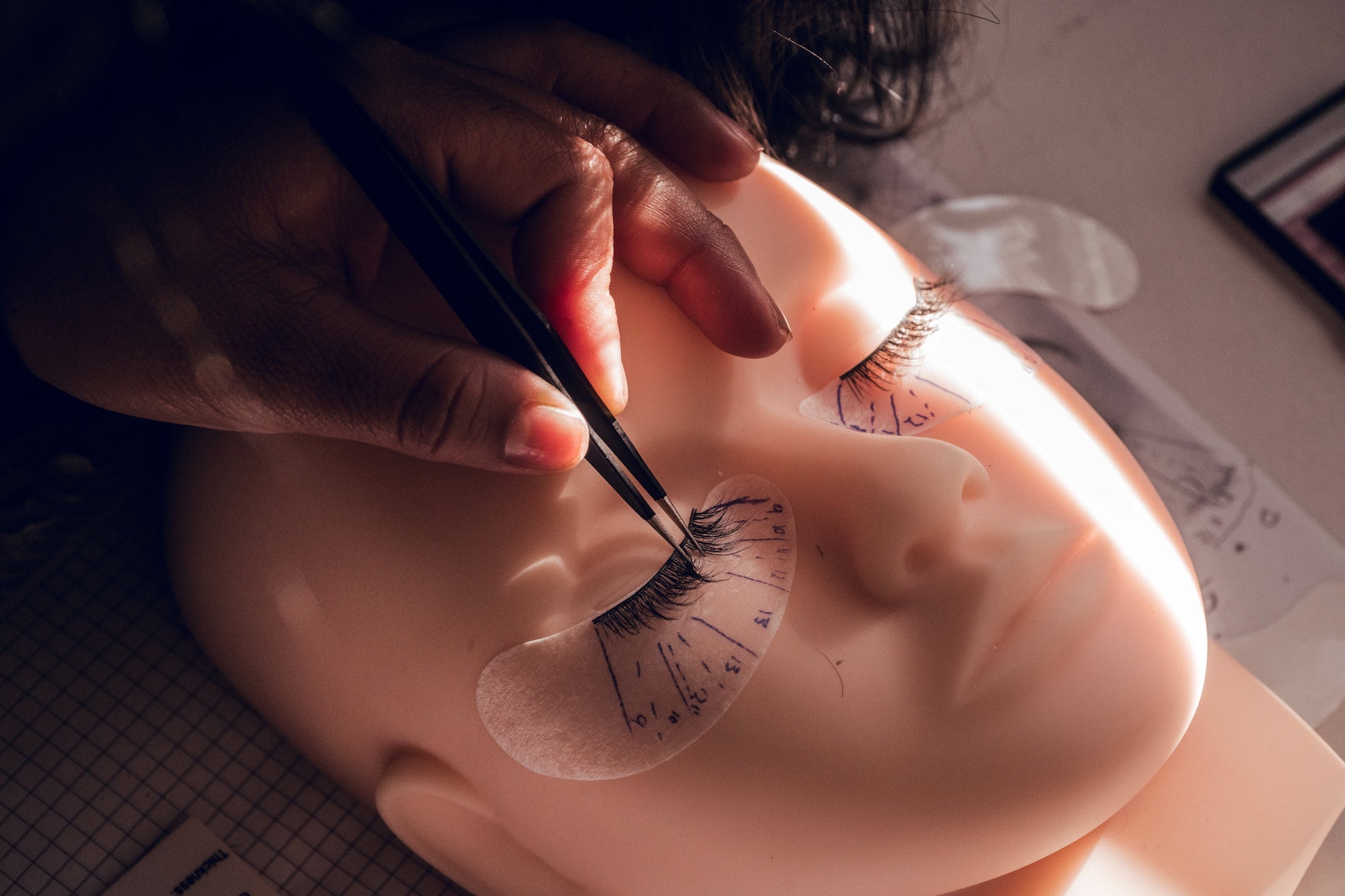 female-hand-putting-false-eyelashes-on-a-mannequin-2023-11-27-05-04-13-utc.jpg